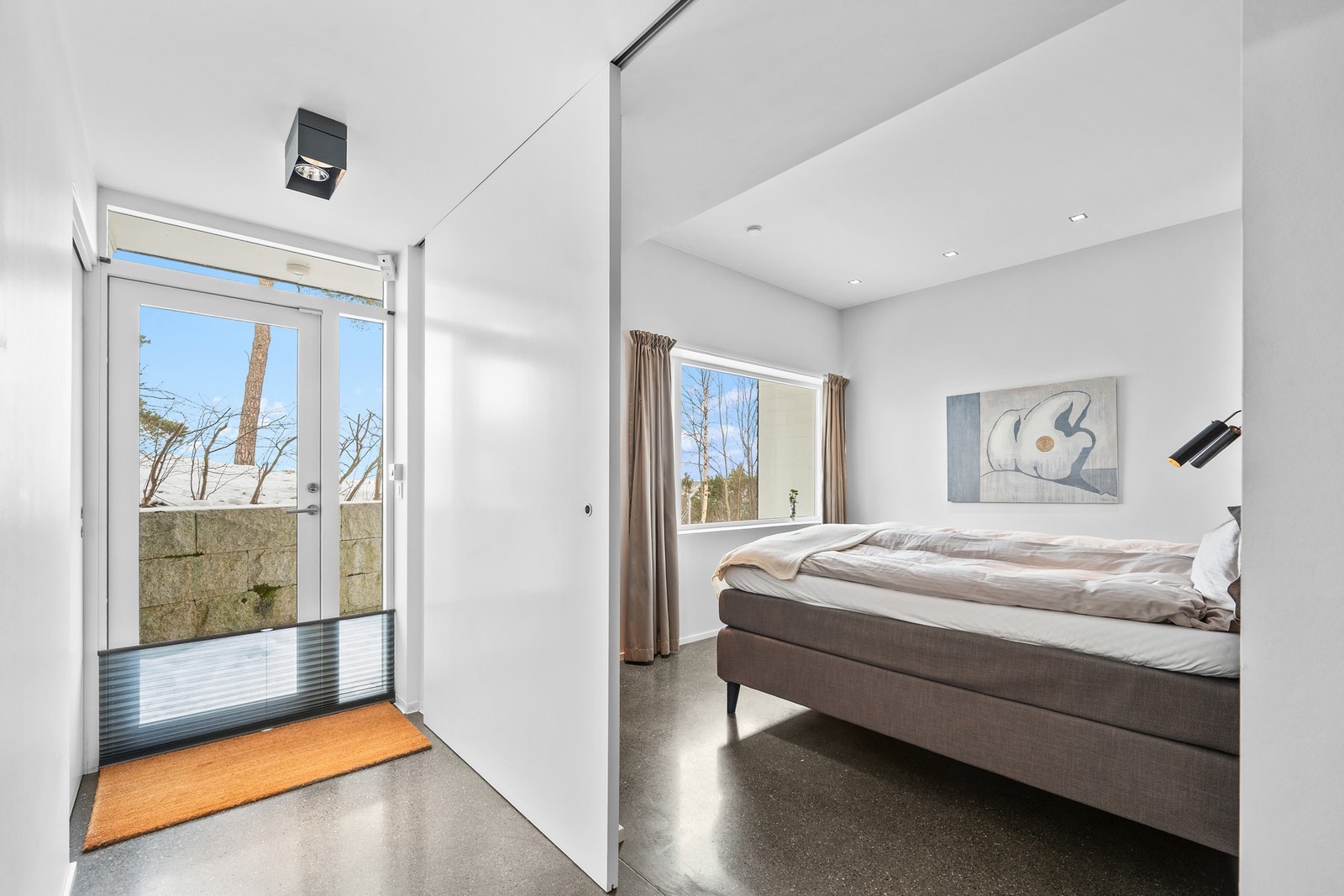 Hovedsoverommet ligger også ytterst på den ene kortenden av huset - ut mot utsikten og hagen. De samme store og flotte skyvedørene som går fra gulv til tak er også benyttet inn til soverommene i underetasjen. Galleribilde