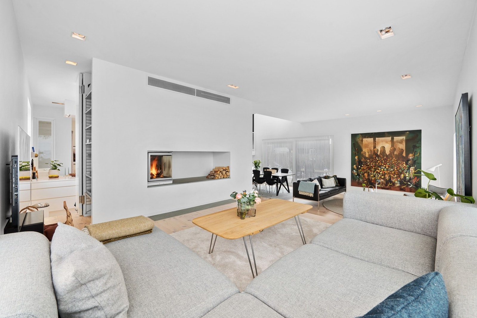 Til venstre i bildet ser man inn mot kjøkkenet - her er det montert dør som går fra gulv til tak, slik at man kan åpne og lukke etter eget ønske. Fine og praktiske plassbygde hyller til høyre for denne døra. Galleribilde