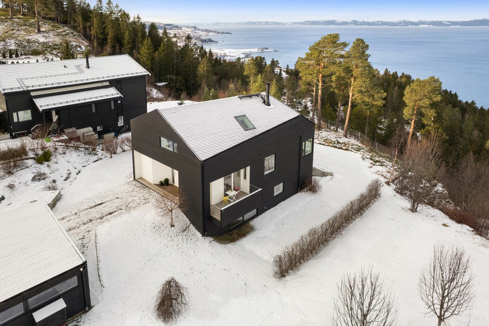 Hage rundt hele huset - fra oversiden ved den største uteplassen/terrassen, videre rundt fremsiden og rundt mot garasjen igjen. Hekken til høyre i bildet viser grensen mot velforeningens tomt, som eiendommen grenser mot. Galleribilde