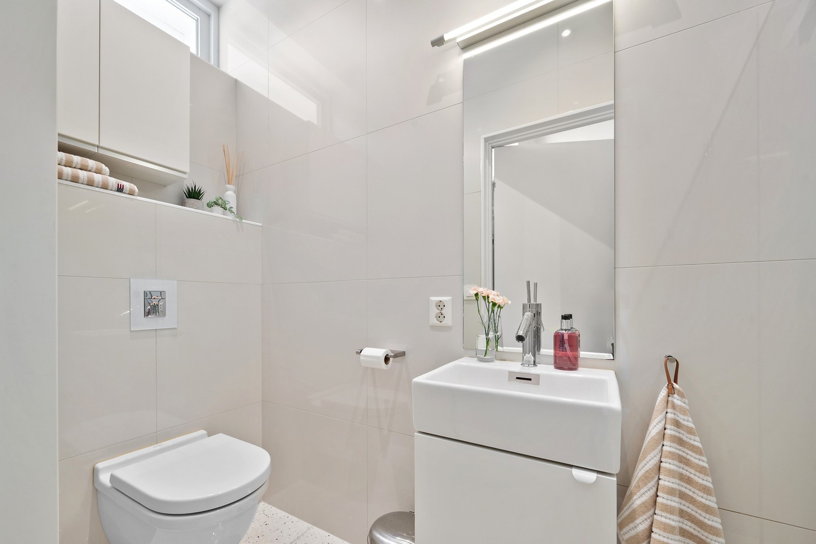 Pent og tidløst bad med vegghengt toalett, servant med skap og dusjnisje. Galleribilde