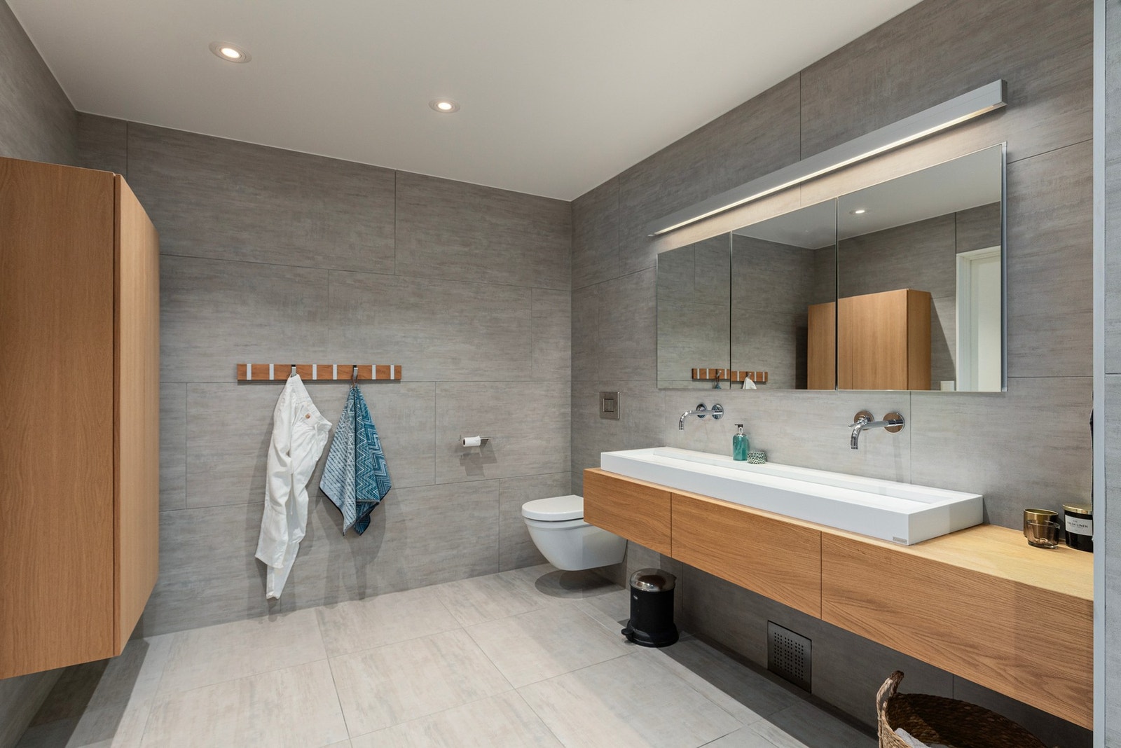 Det naturlige og organiske uttrykket mht. materialvalg, mot rustikke gråtoner fungerer svært godt. Flotte veggmonterte servantarmatur, praktiske speilskap, samt godt med oppbevaringsplass ellers. Galleribilde