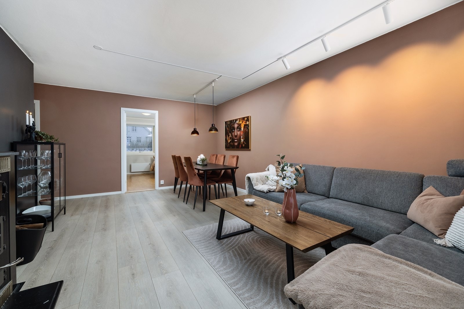 Stuen oppleves som hyggelig og varm med 1-stavs laminat på gulv og slette vegger malt i en moderne og trendy, rust rød fargetone. Galleribilde