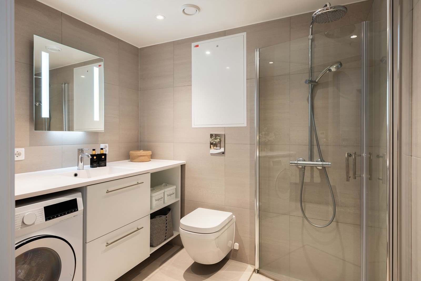 Badet er utstyrt med mekanisk avtrekk, servant i servantskap, rørfordelingsskap, opplegg for vaskemaskin, innfellbare dusjdører og veggmonte wc. Galleribilde