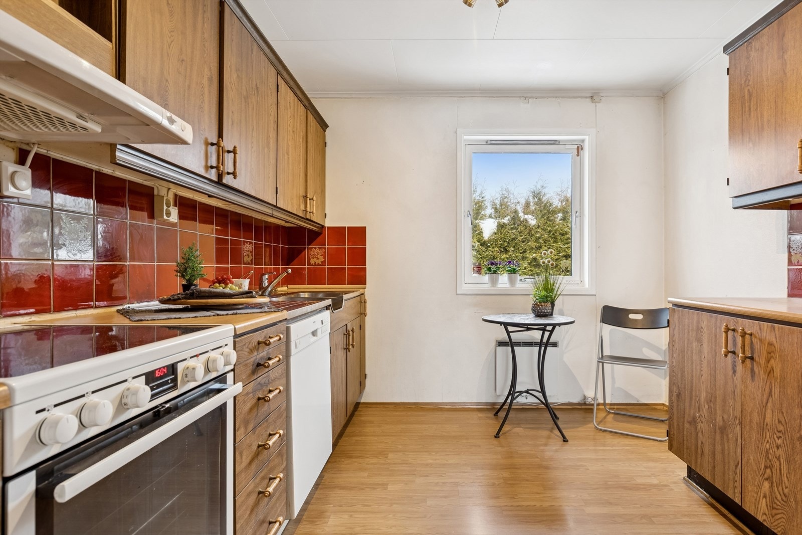 Det er fliser mellom benk og overskap, samt belysning og stikkontakter under overskapene. Galleribilde