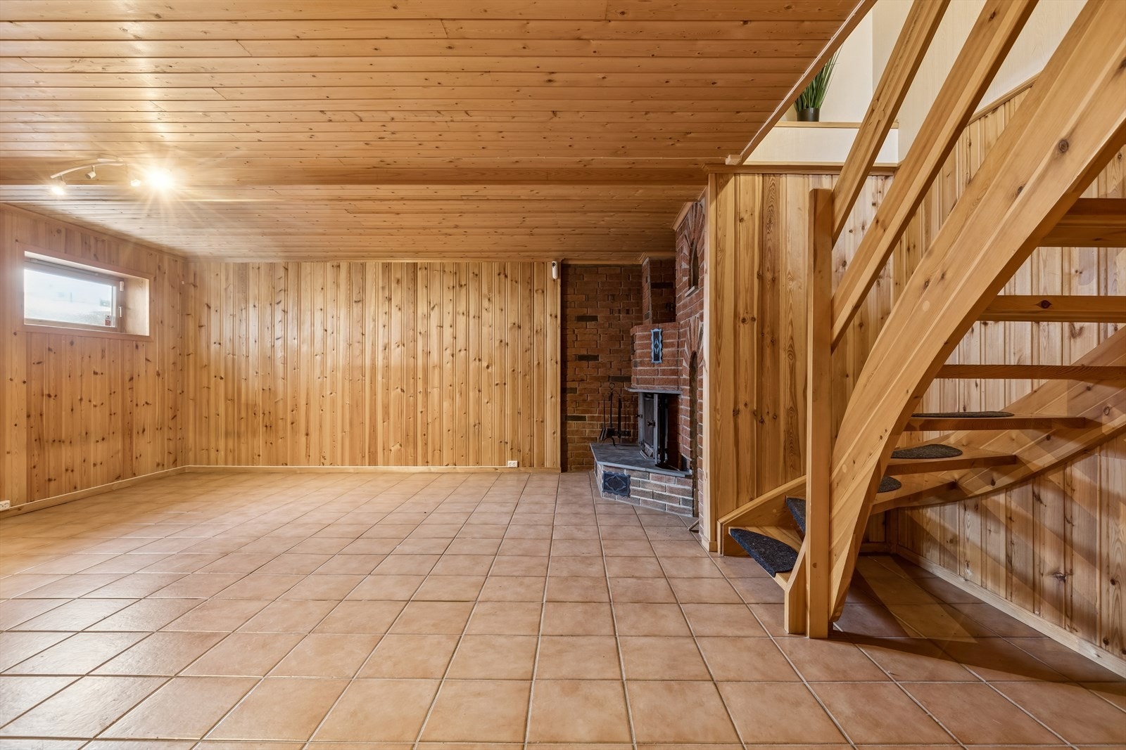 Innredet rom i kjeller er et romslig rom med flislagt gulv og trepanel på vegger og i tak. Galleribilde