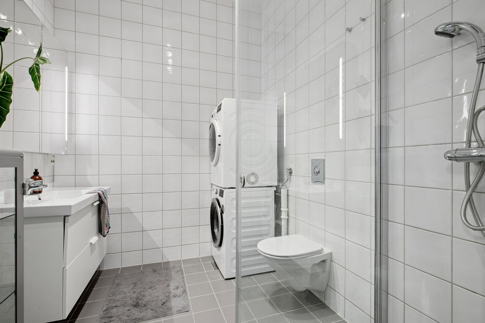 Baderommet er tidløst innredet med grå fliser på gulvet og hvite fliser på vegg. I gulvet har man også varmekabler for ekstra komfort. Galleribilde