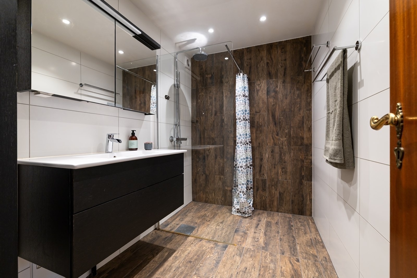 Hovedbadet er flislagt og innredet med en romslig dusjnisje og servantmøbel. Galleribilde