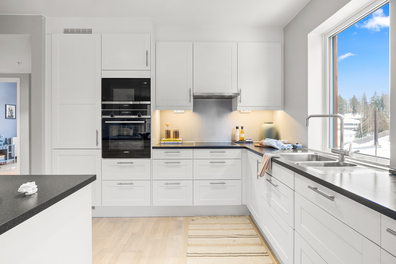 Moderne og stilrent kjøkken med integrerte hvitevarer, god skap- og benkeplass samt praktisk arbeidsflyt. Store vindusflater gir rikelig med naturlig lys. Galleribilde