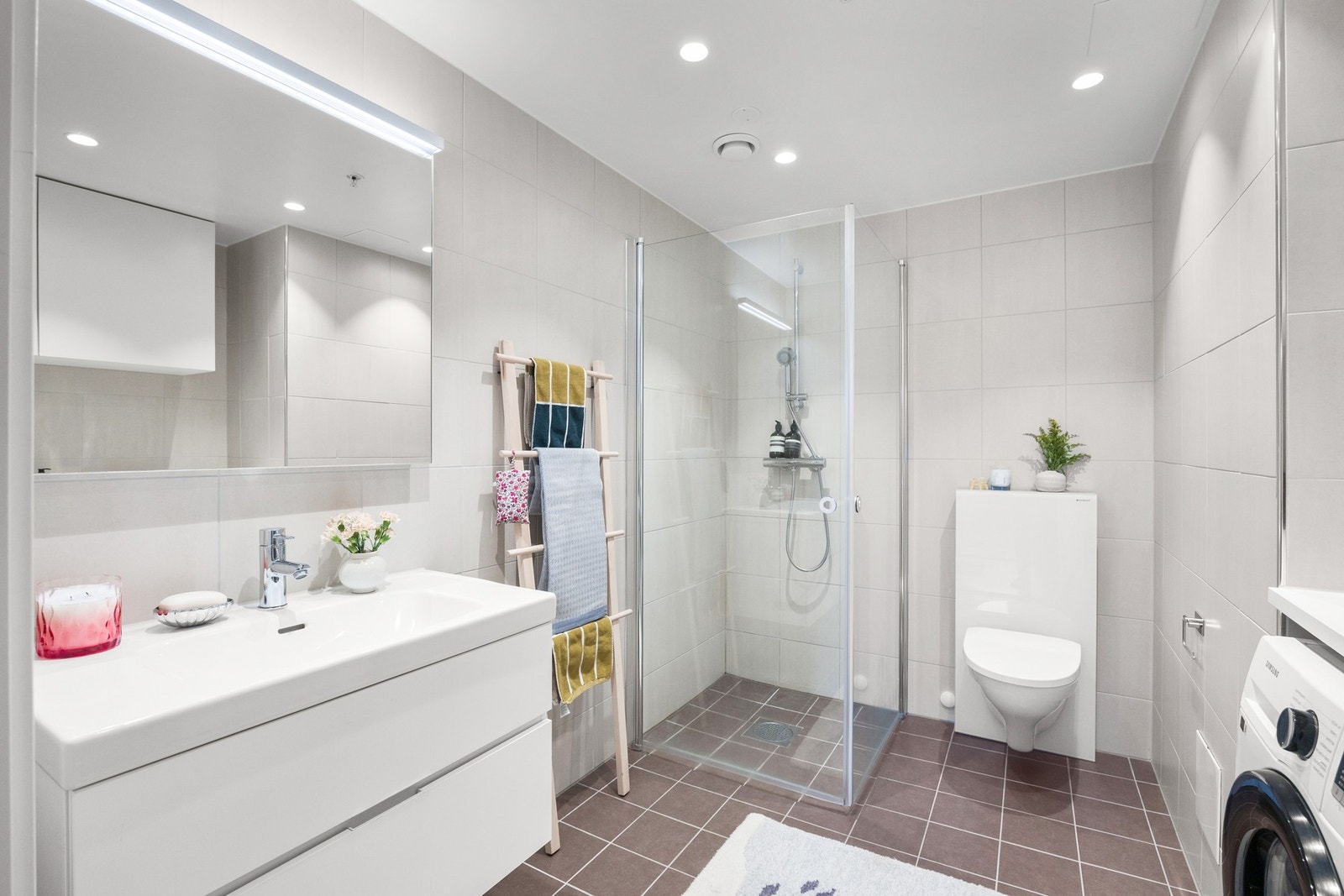 Stilrent bad med dusjhjørne i glass og vegghengt toalett. Gjennomført uttrykk og funksjonell løsning. Galleribilde