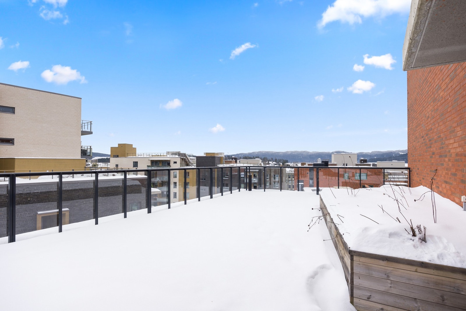 Romslig terrasse med god bredde og åpent utsyn mot omkringliggende bebyggelse og landskap. Rekkverk i glass gir et luftig uttrykk og gode siktlinjer. Galleribilde
