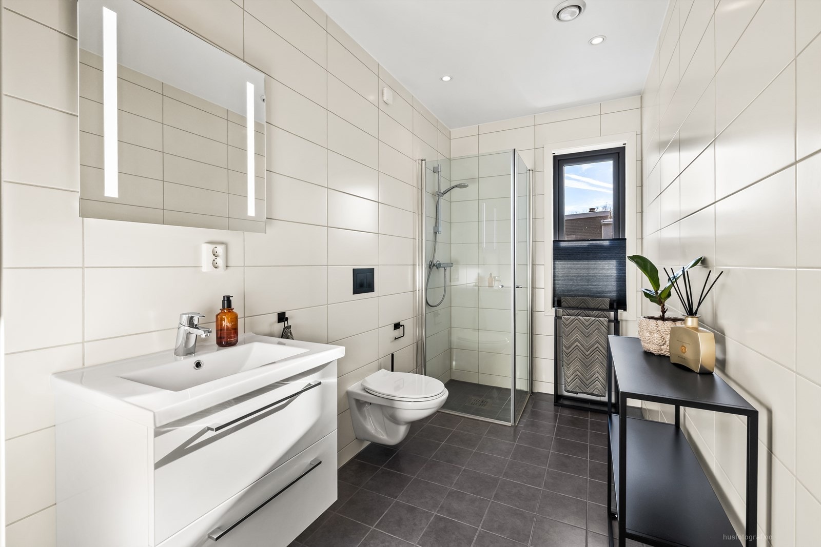 Innredet med lys servantinnredning med nedfelt servant, med dusjhjørne og toalett. Galleribilde