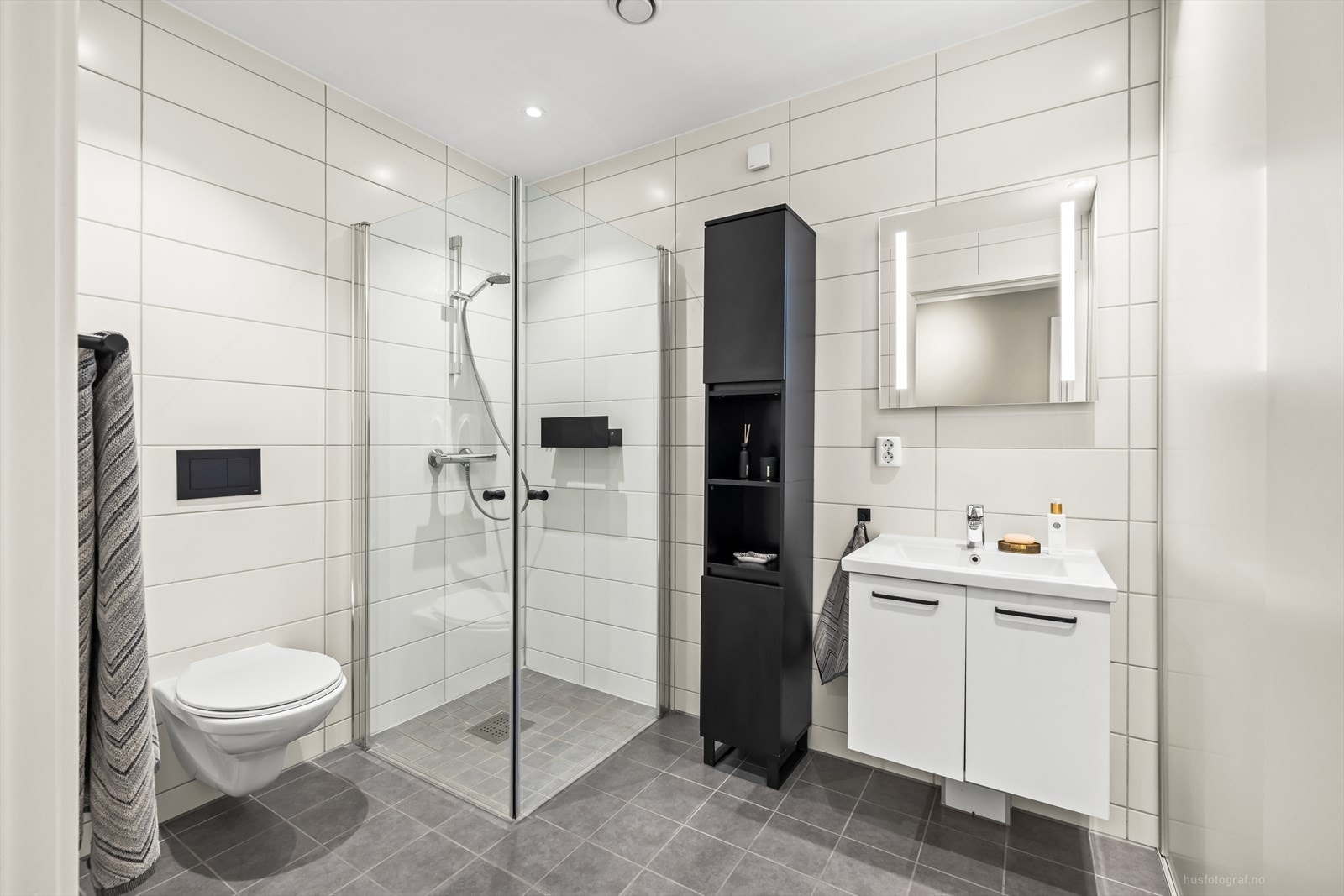 Baderomsinnredning i lys utførelse med heldekkende nedfelt servant, rom for oppbevaring i skuffer og speil med belysning. Galleribilde