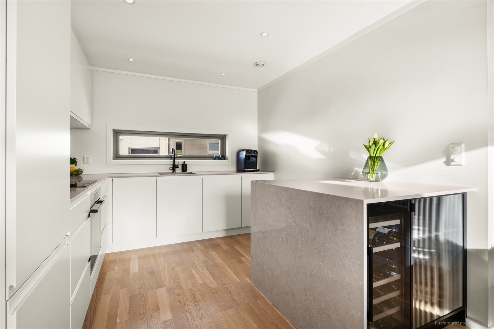 Den romslige innredningen fungerer både som en praktisk arbeidsflate og som en kjøkkenøy med integrert vinskap. Galleribilde