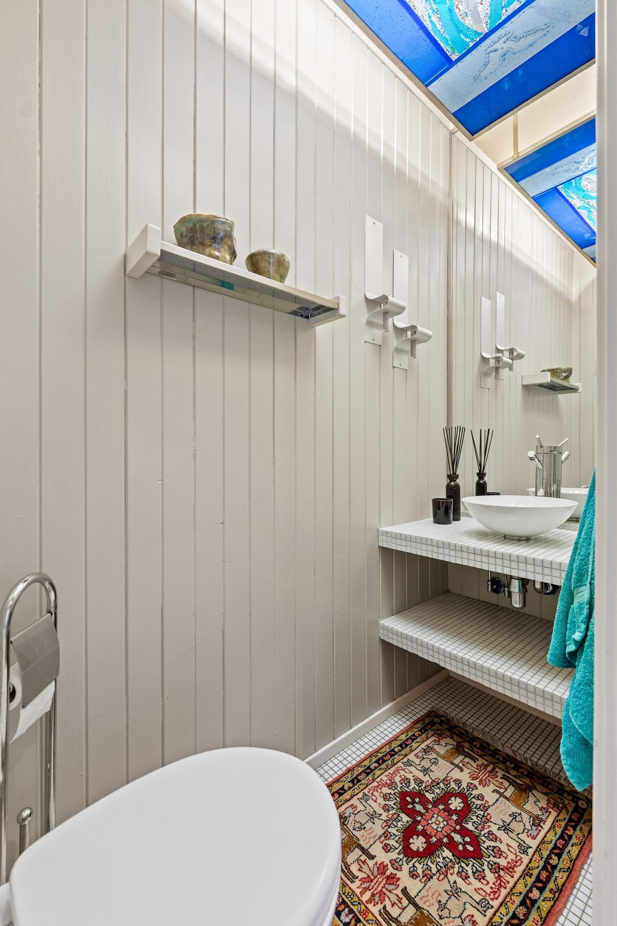 Toalettrommet i boligens 2. etasje kombinerer klassiske materialvalg med unike detaljer. Et blikkfang i rommet er det stilige maleriet i himlingen, som tilfører en kunstnerisk og personlig touch. Galleribilde