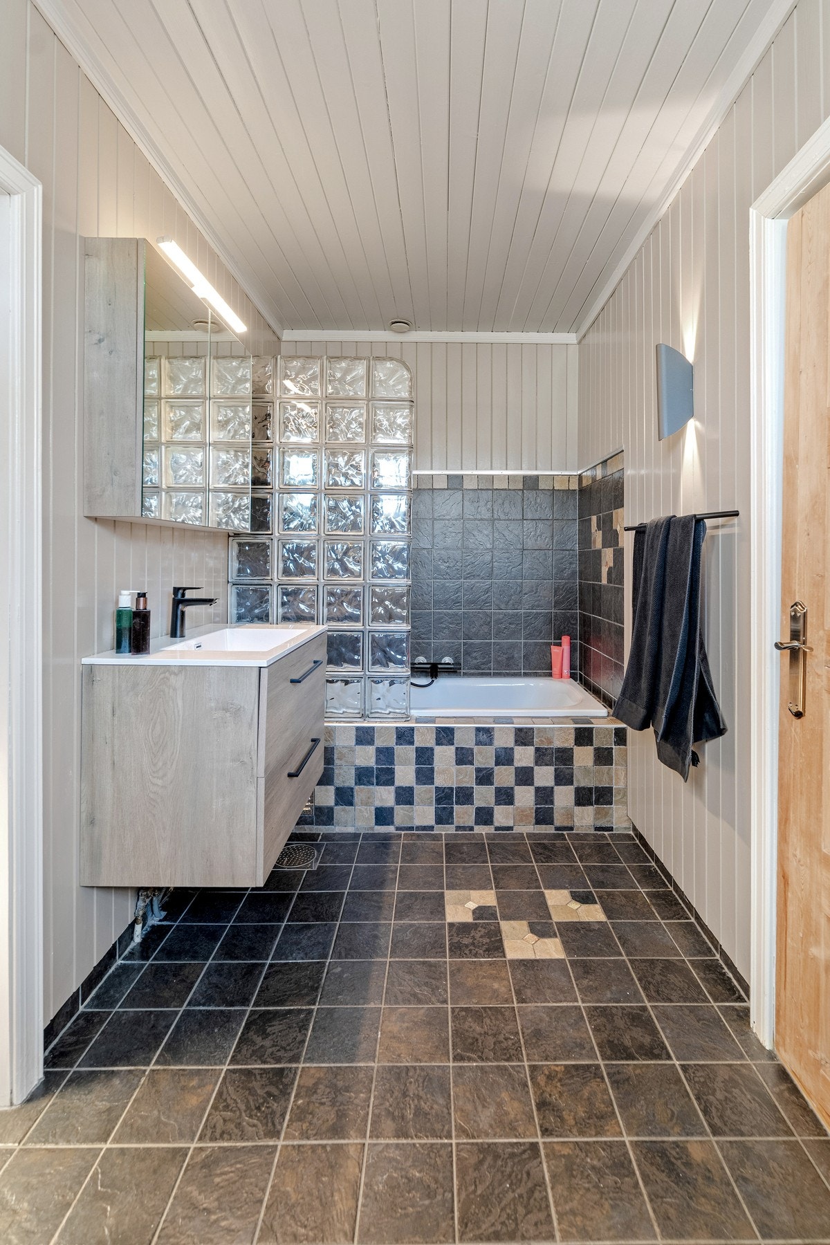 Badet i andre etasje er romslig og praktisk innredet. Her finner du en dusjløsning i innmurt badekar - perfekt for både avslappende bad og effektiv dusj i en travel hverdag. Galleribilde