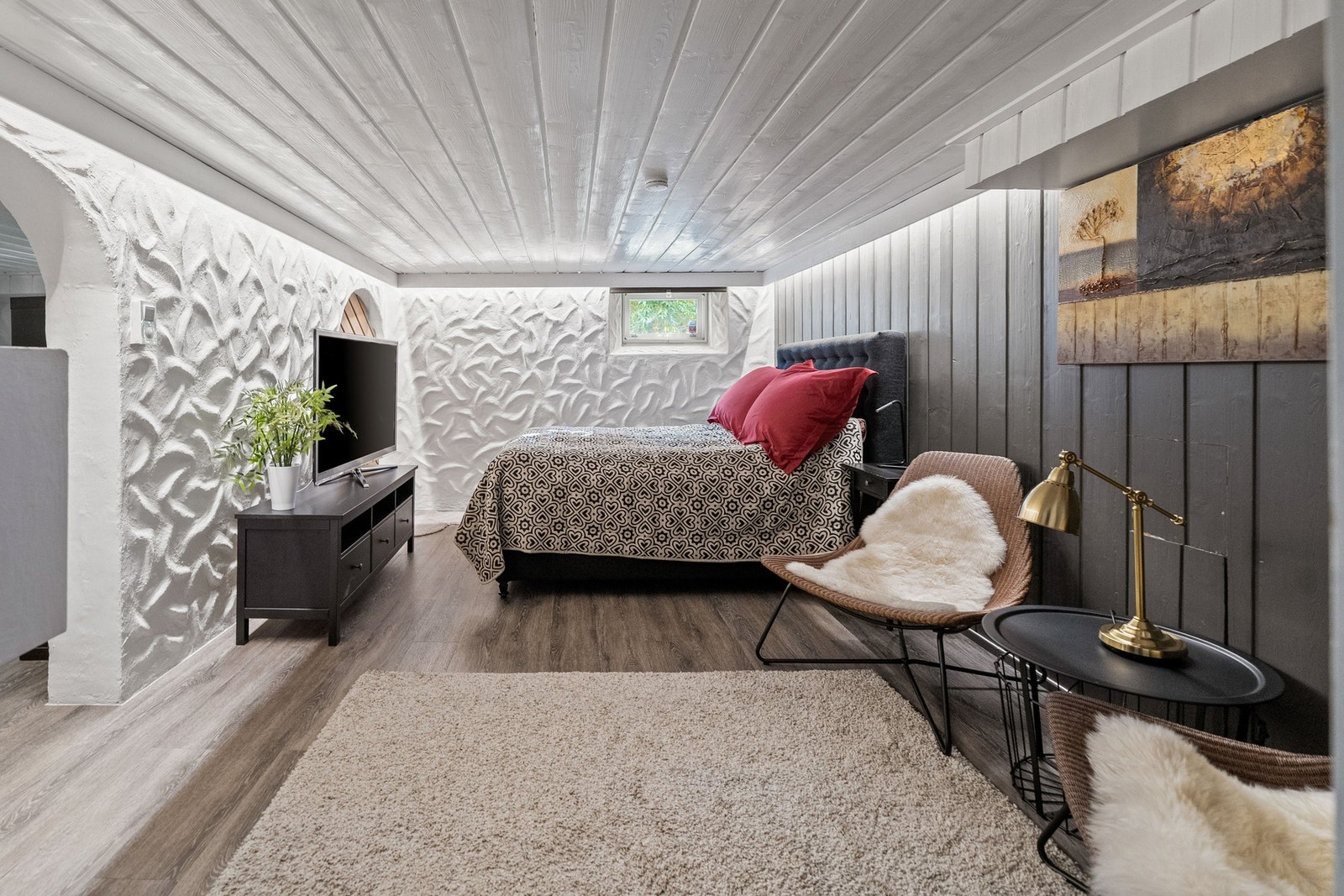 Gulvet er belagt med slitesterkt og lettstelt laminat, som gir en moderne og ren overflate. Veggene består av en kombinasjon av hvitmalt murverk og mørk trepanel, noe som skaper en spennende kontrast mellom det lyse og det lune. Galleribilde