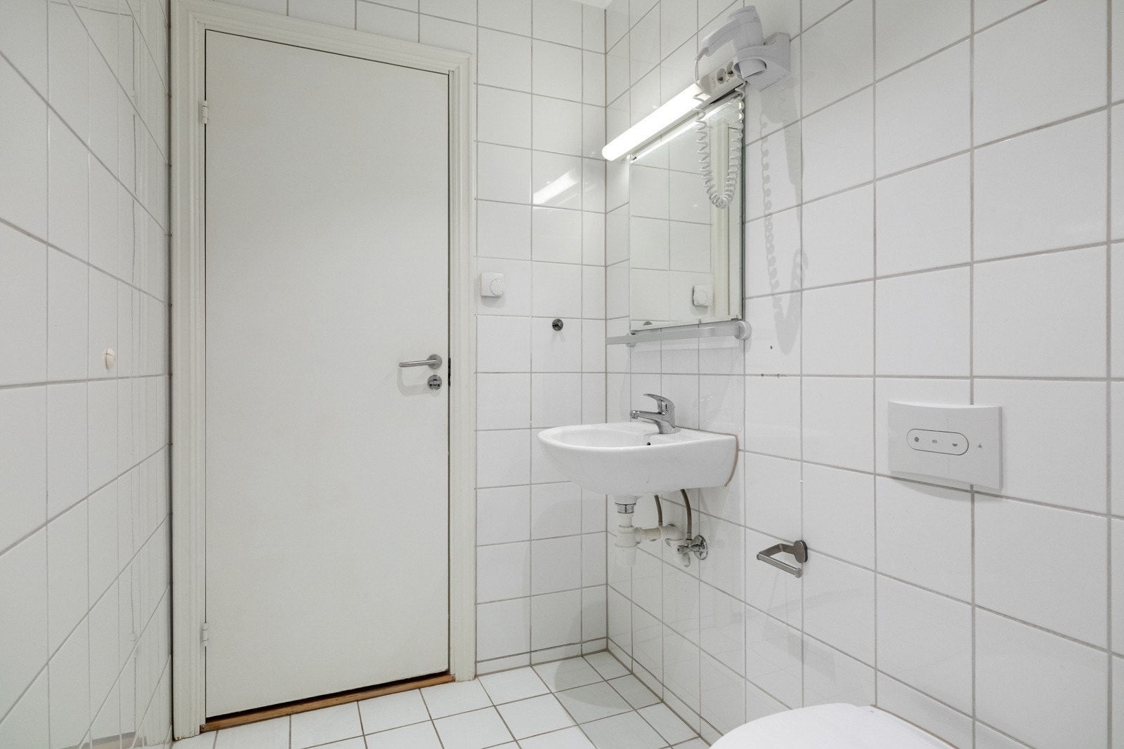 Baderommet er utstyrt med vegghengt servant med speil og belysning over, dusjhjørne med forheng, vegghengt toalett og opplegg for vaskemaskin. Galleribilde