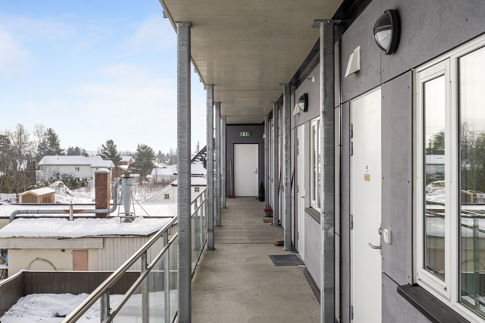 Felles svalgang med betonggulv og glassrekkverk frem til leiligheten. Galleribilde