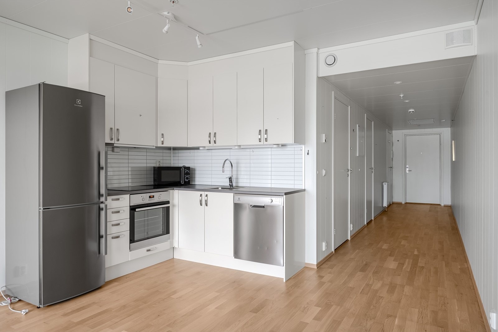 Kjøkkeninnredning i vinkel med glatte, lyse fronter. Galleribilde