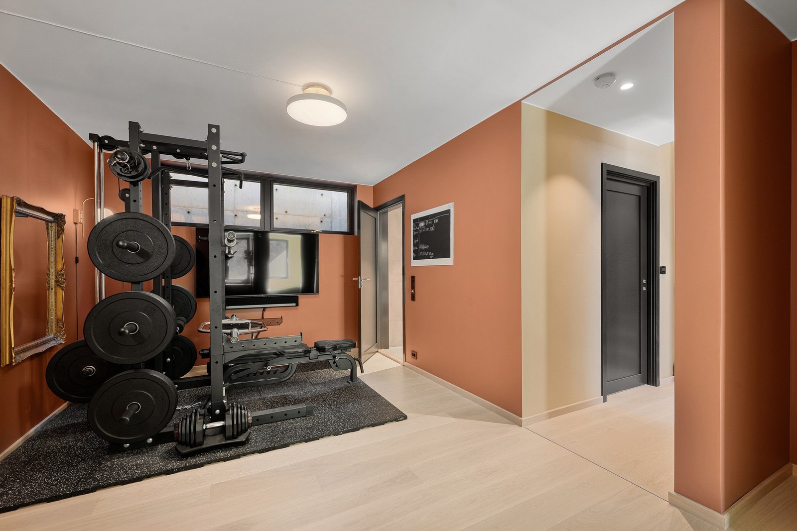 Oppholdsrommet i underetasjen brukes i dag som treningsrom, og fungerer som en fleksibel ekstra sone som kan tilpasses ulike behov - som TV-stue, lekerom, hobbyrom eller hjemmekontor. Galleribilde