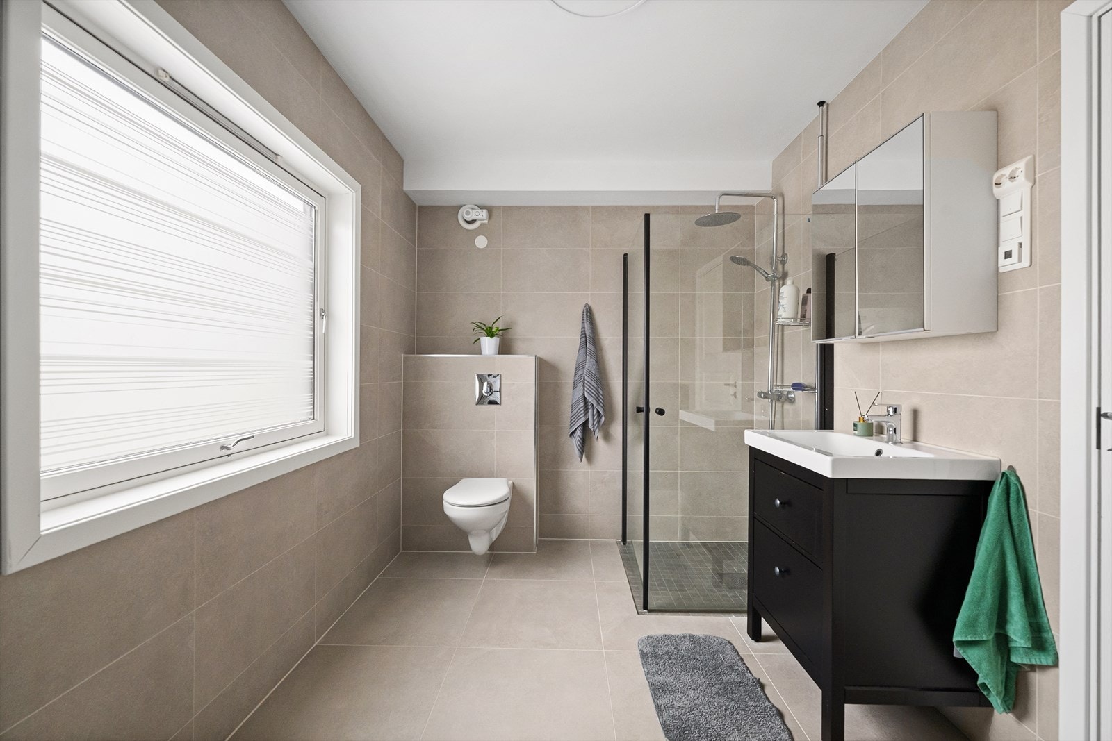 Flott bad fra 2018 med nedfelt servant, veggmontert toalett, dusjdører og opplegg for vaskemaskin Galleribilde