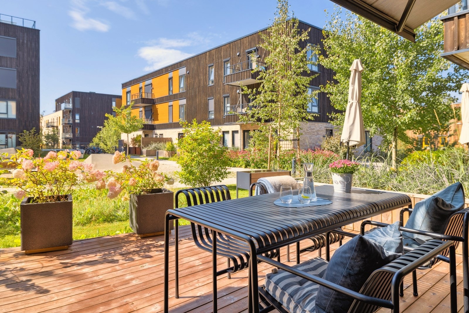 Uteområdet er en grønn oase med plen og beplantning som rammer inn terrassen. Et særdeles koselig og stille område. Galleribilde