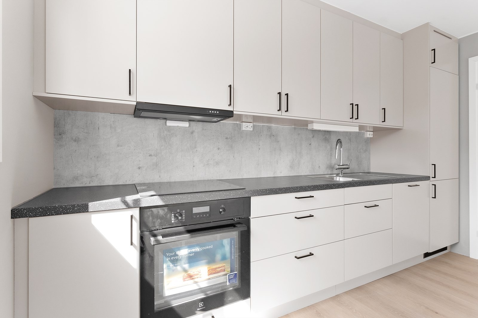 Nedfelt stålkum, grå plater over benk og ventilator over kokesonen gir et gjennomført uttrykk. Kjøkkenet har hele 25 års funksjonsgaranti. Galleribilde