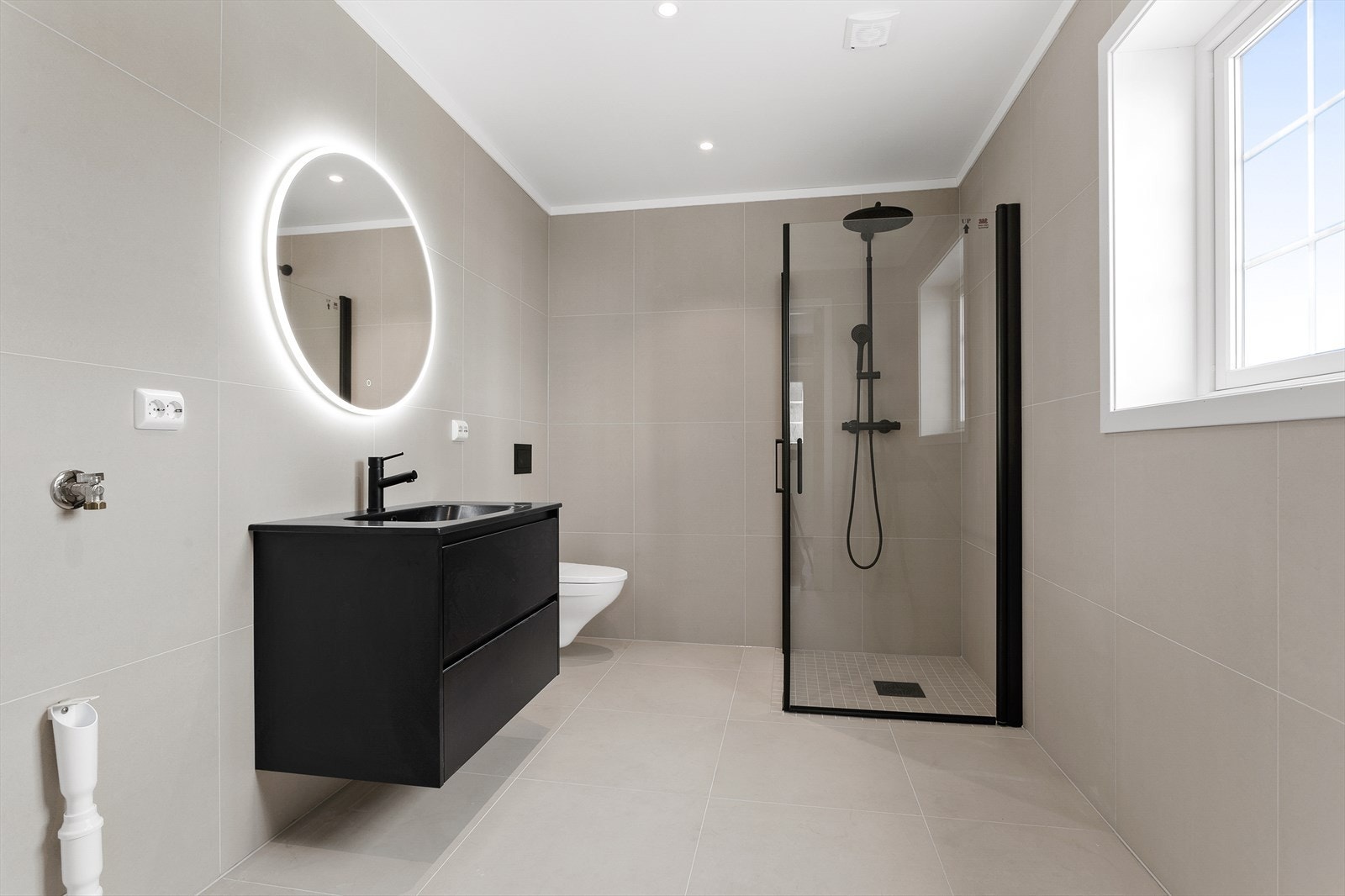 Rommet er utstyrt med vegghengt toalett, opplegg for vaskemaskin og et elegant dusjhjørne med regnfallsdusj og innfellbare glassvegger. Galleribilde