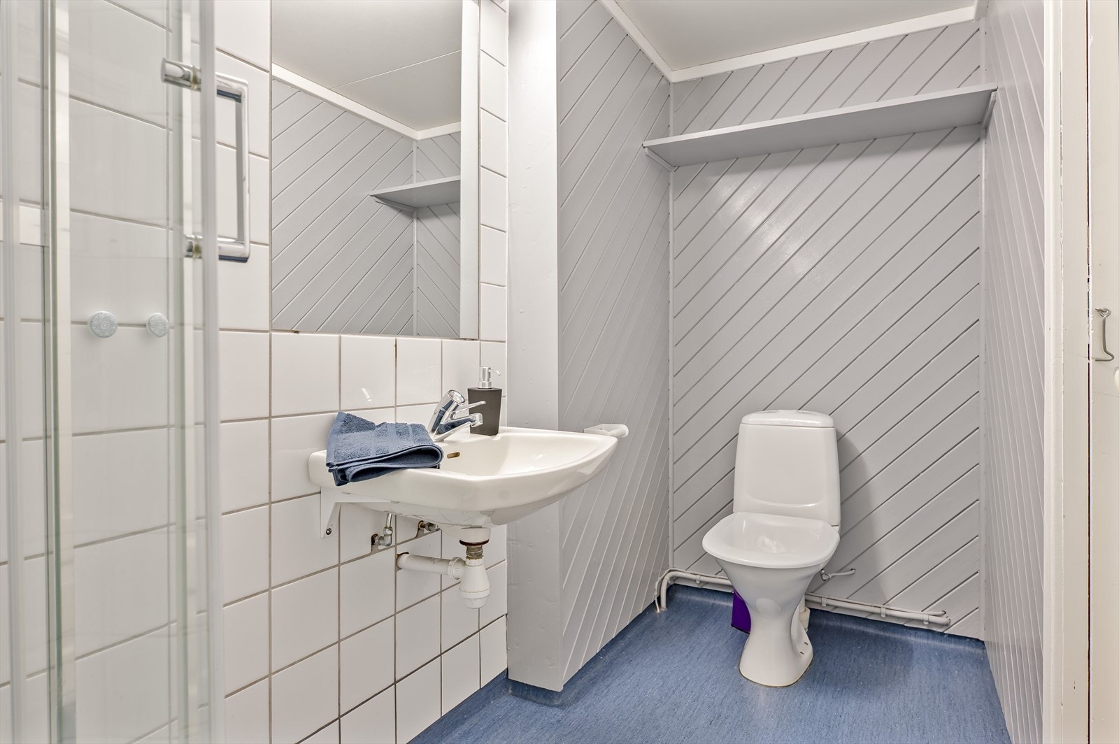 Baderommet er utstyrt med vegghengt servant med speil over, dusjkabinett og gulvstående toalett. Galleribilde