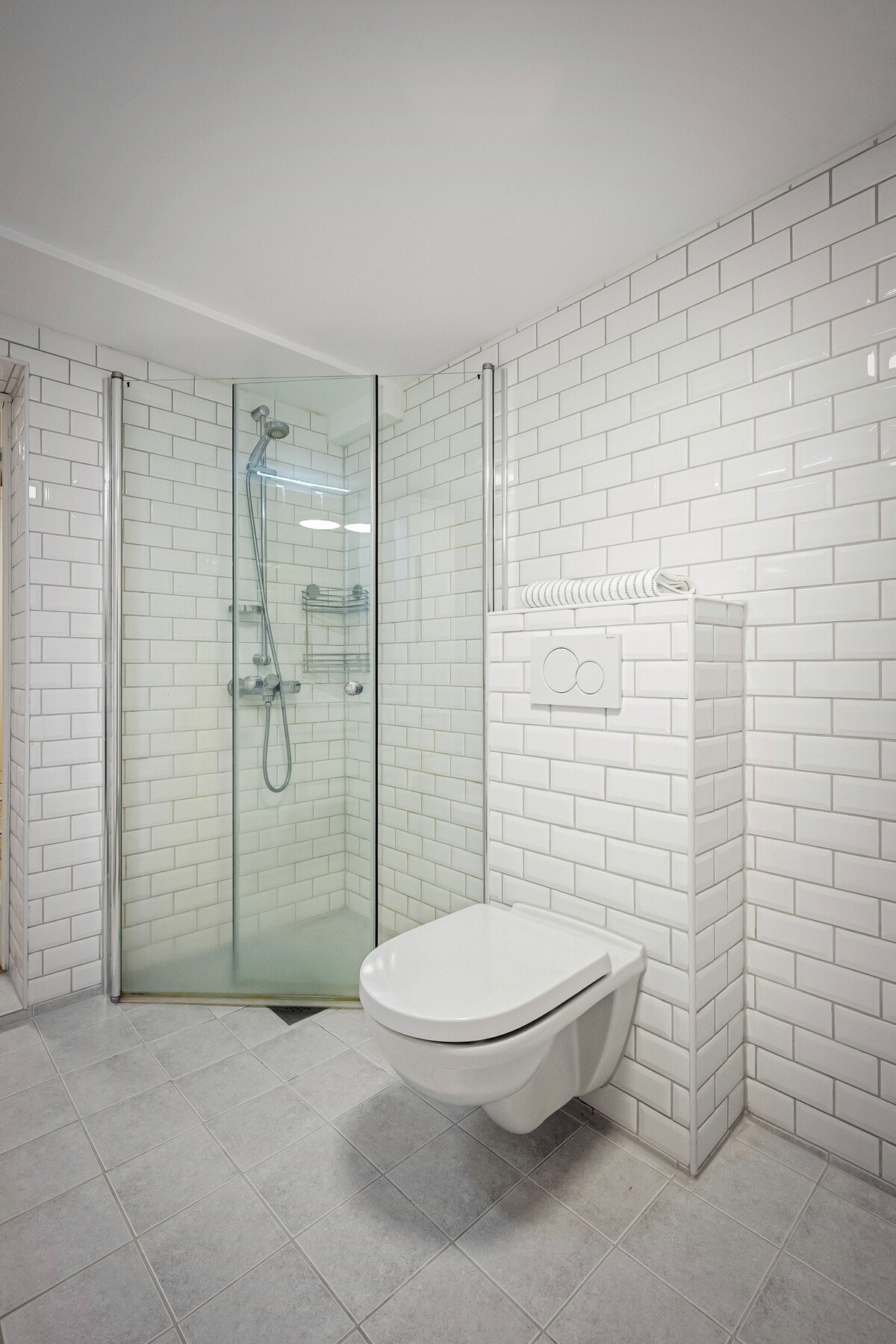 Det er flislagt med varme i gulv, vegghengt toalett, servantinnredning og dusjhjørne med glassdører. Galleribilde