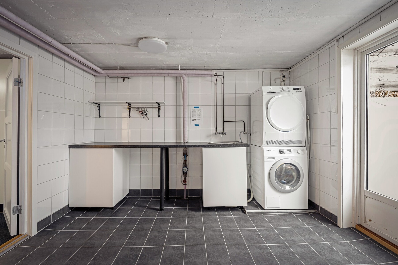 Separat vaskerom gir en svært praktisk løsning for klesvask. Rommet er flislagt og har god plass til vaskemaskin og tørketrommel, samt arbeidsbenk og utslagsvask. Galleribilde