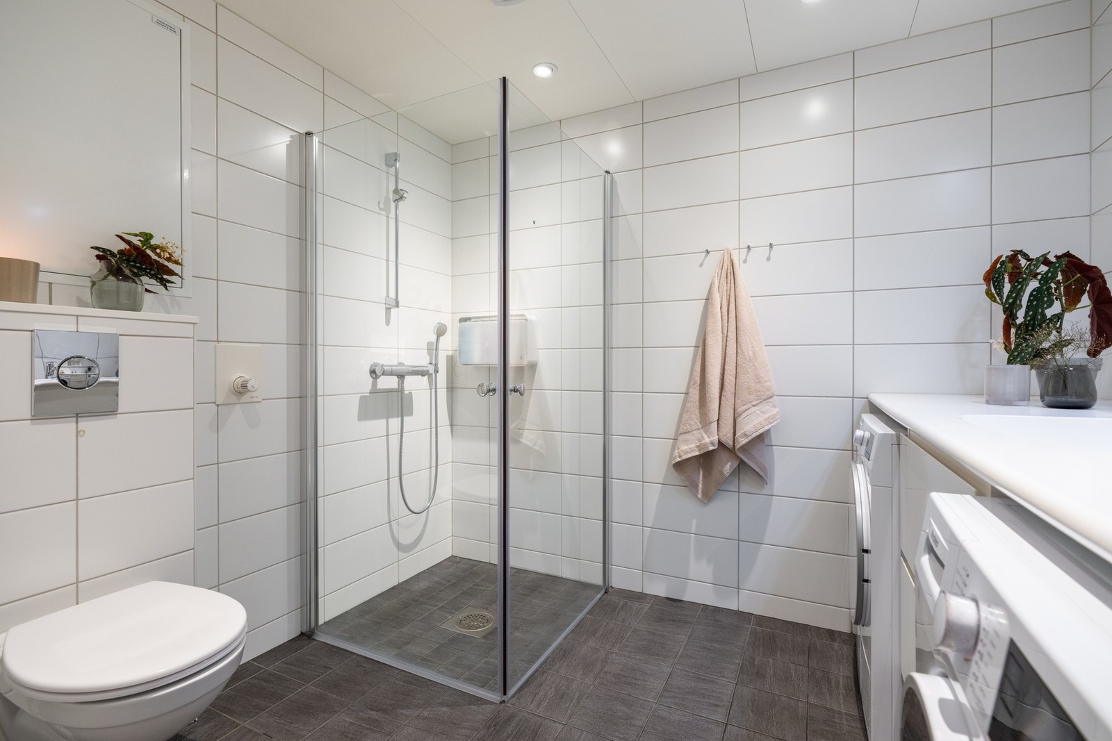 Videre er det vegghengt toalett og dusjhjørne med svingbare glassdører som frigjør plass på gulv. Galleribilde