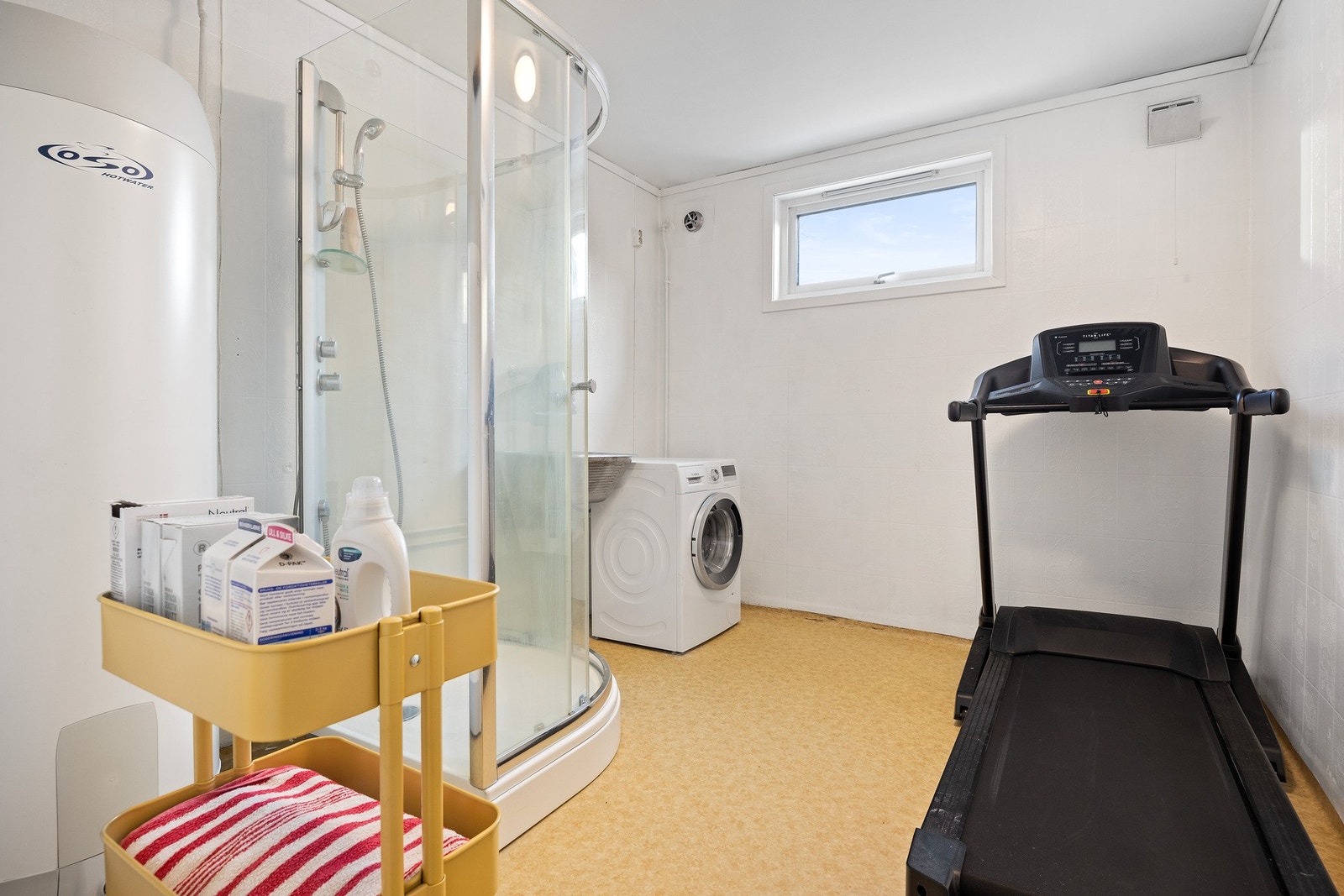 Bad/vaskerom innredet med utslagsvask, dusj og opplegg for vaskemaskin. Galleribilde