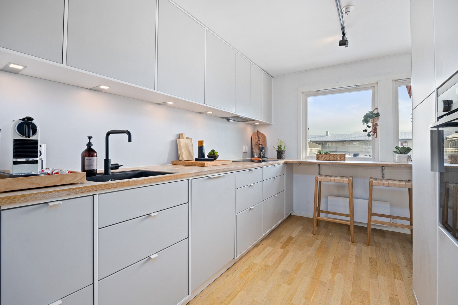 Kjøkkeninnredning i lys gråtone fra Kvik med integrerte hvitevarer. Galleribilde