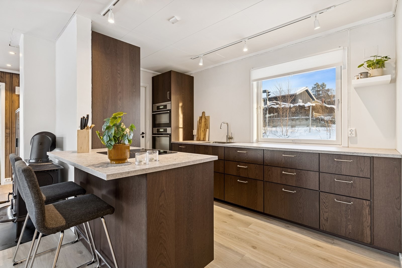 Moderne kjøkkeninnredning med mørke, slette fronter og rikelig med skap- og benkeplass. Galleribilde