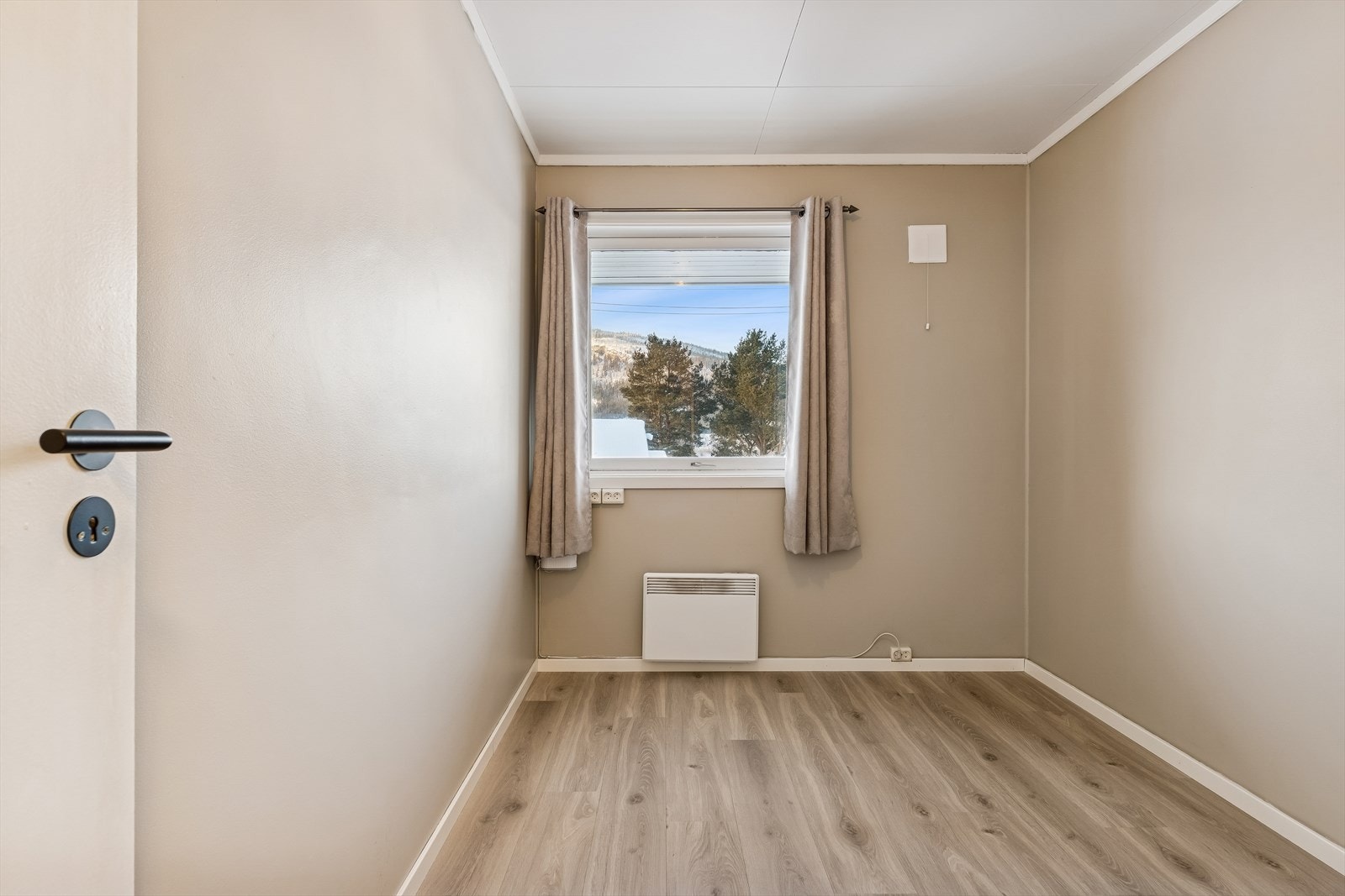 Boligens andre soverom har en nøytral fargepalett og laminat på gulvet. Galleribilde