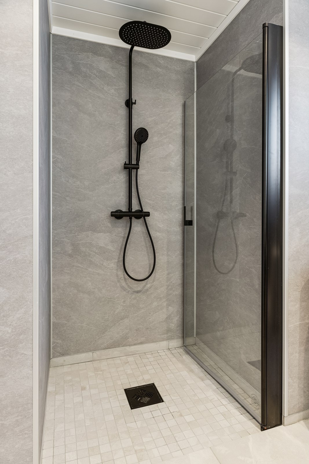 Dusjhjørnet har innfellbare glassdører og en sort regnfallsdusj. Galleribilde