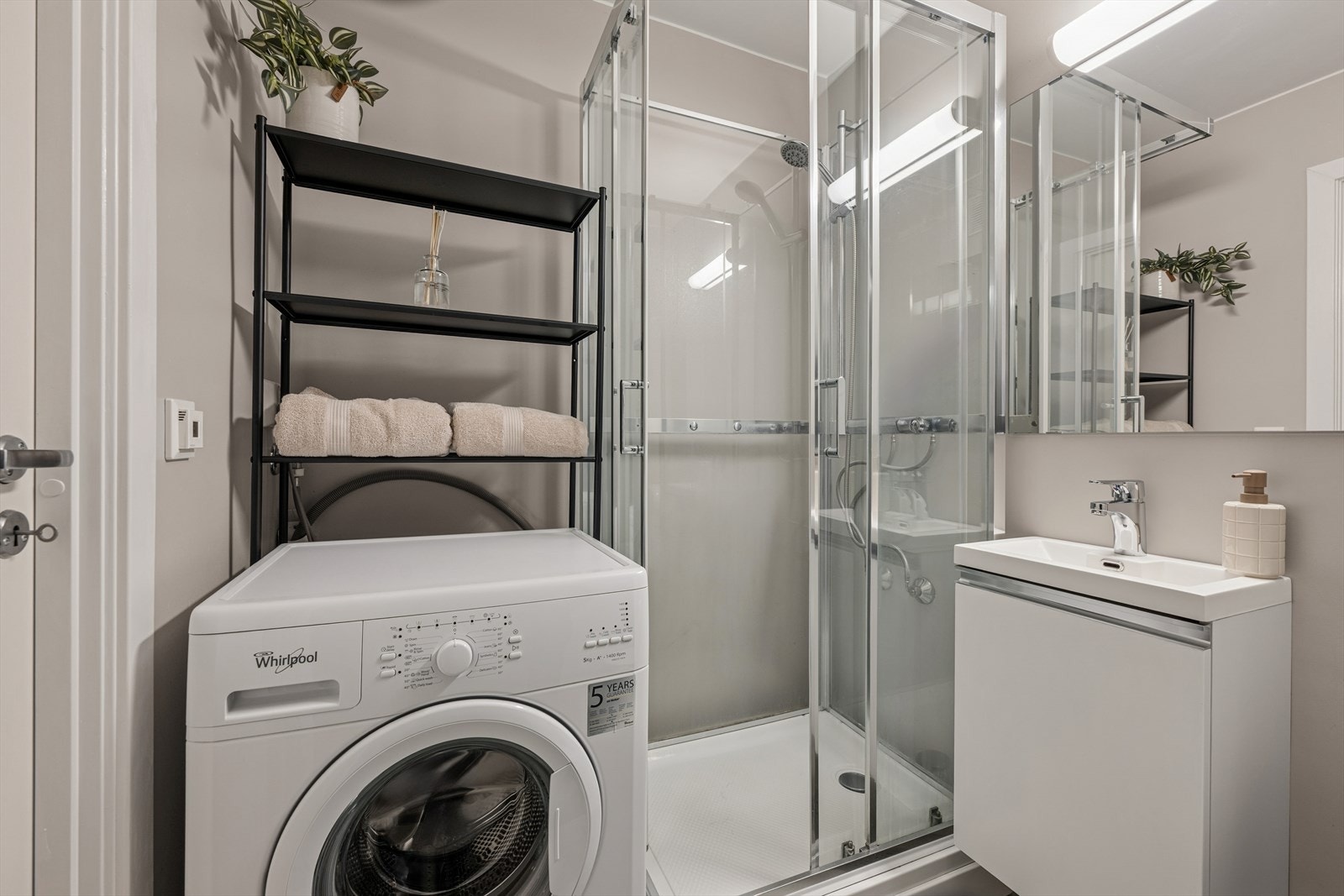 Badet er utstyrt med dusjkabinett, opplegg til vaskemaskin, servant m/speil og toalett Galleribilde