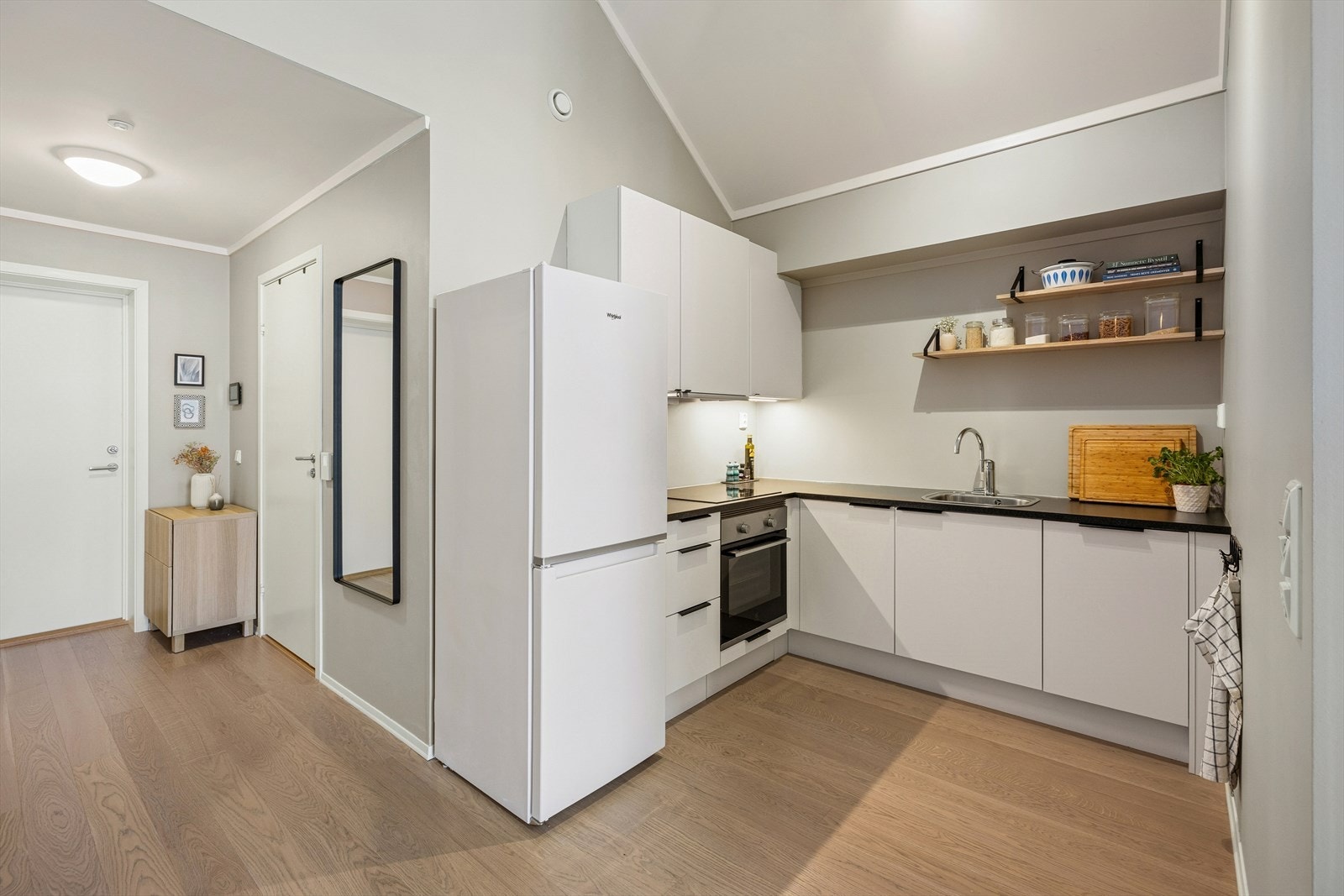 Kjøkkenet har en innredning med glatte fronter, laminerte skrog og en laminert benkeplate med belysning over. Galleribilde