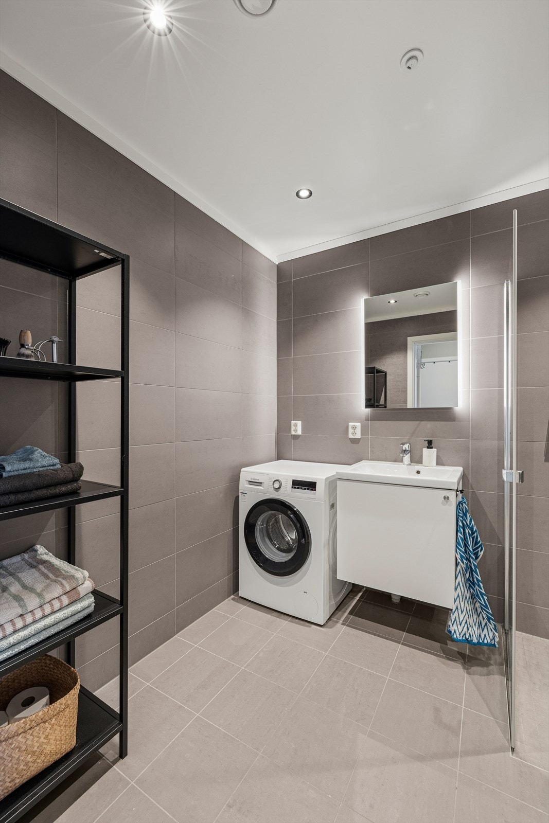 Innredningen består av en servant med underskap, speil med belysning, dusjdører, vegghengt toalett og opplegg for vaskemaskin. Galleribilde