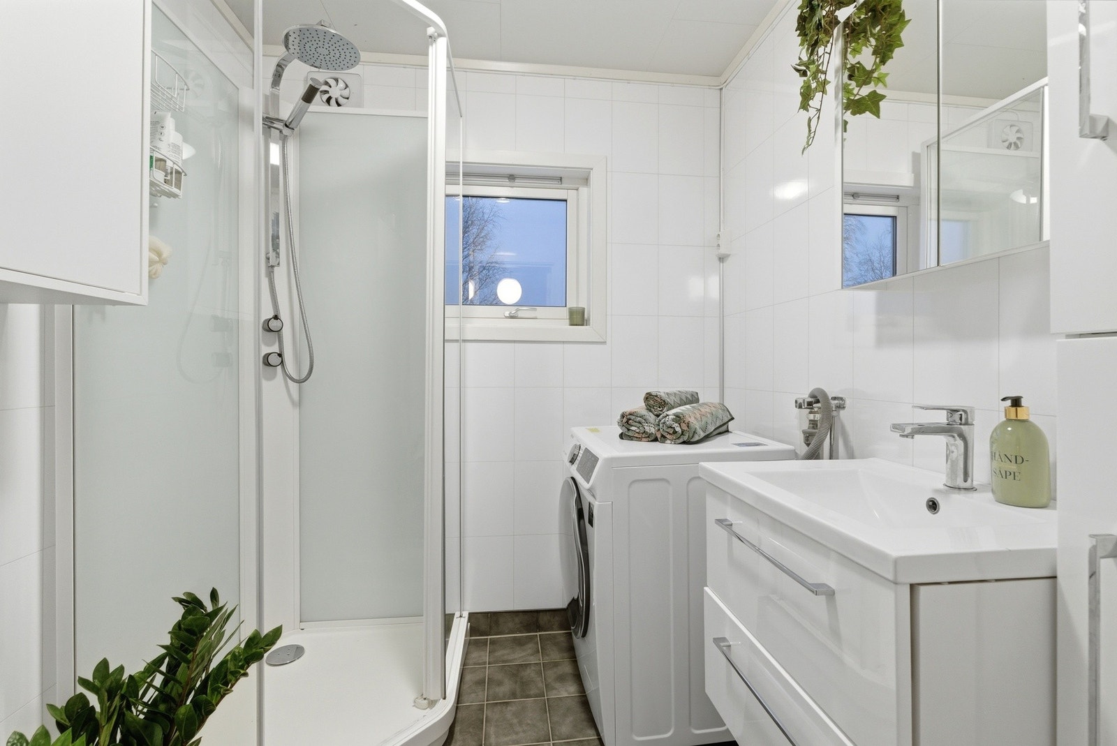 Badet er lyst og innbydende, og med varmekabler i gulvet. Her er det dusjkabinett og servant i innredning, wc og plass til vaskemaskin Galleribilde