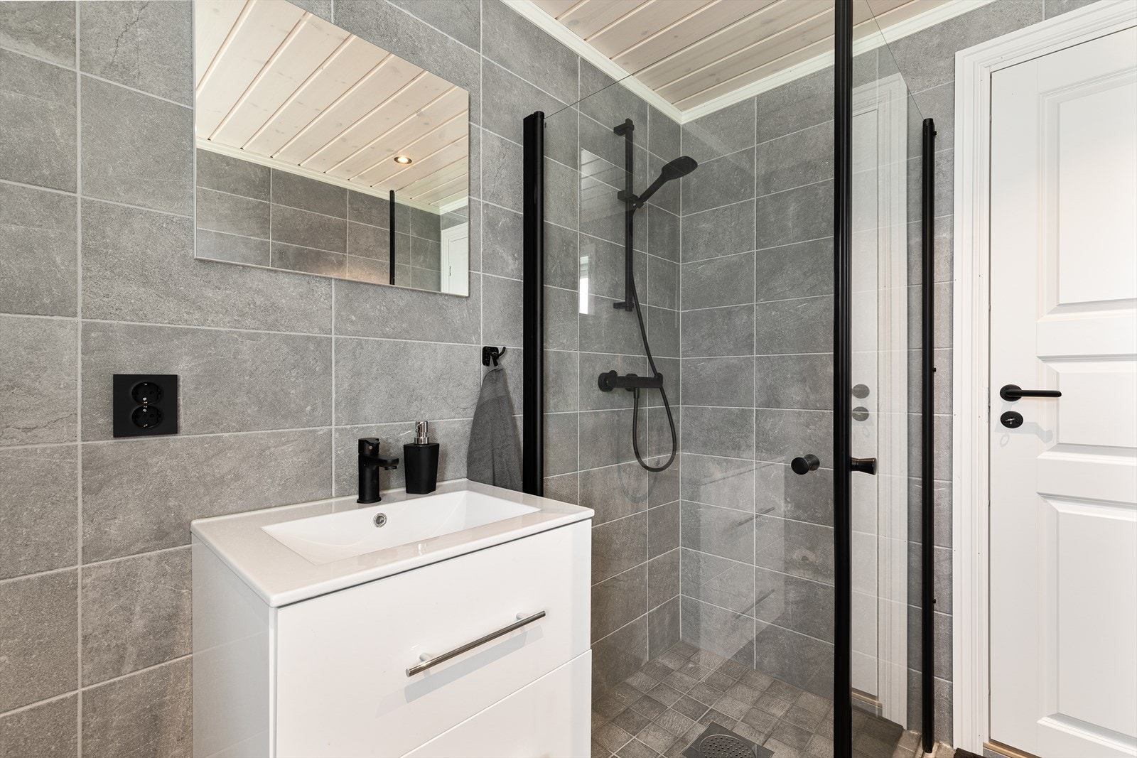 Badet er utstyrt med toalett, dusj og servant med innreiing. Downlights i tak Galleribilde