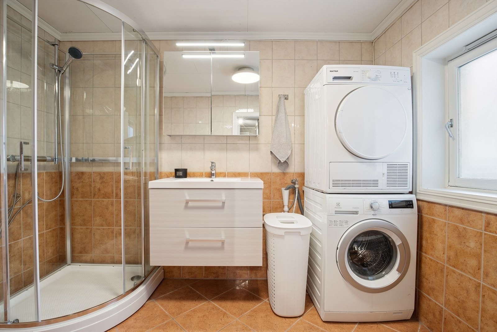 Badet er ellers utstyrt med dusjkabinett, vegghengt toalett og nyere baderomsinnredning med god lagringsplass og nedfelt servant. I tillegg har man opplegg for vaskemaskin og plass til tørketrommel. Galleribilde