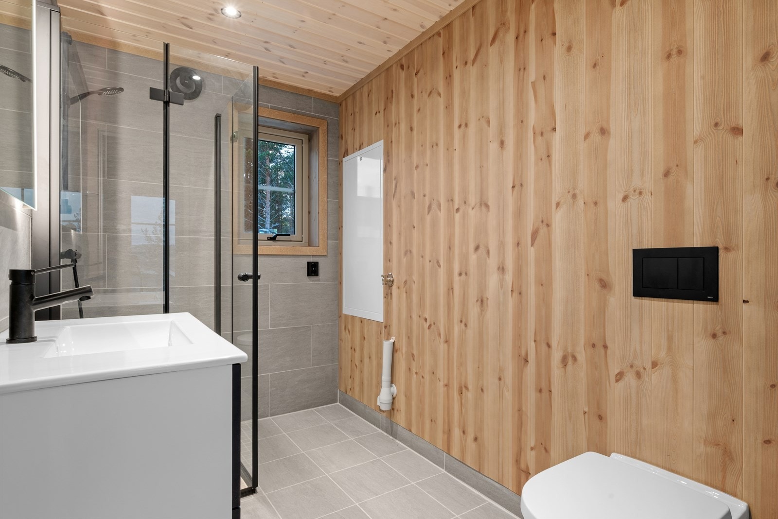 Baderommet er moderne og smakfullt innredet med lyse grå fliser på gulv og to vegger. Galleribilde