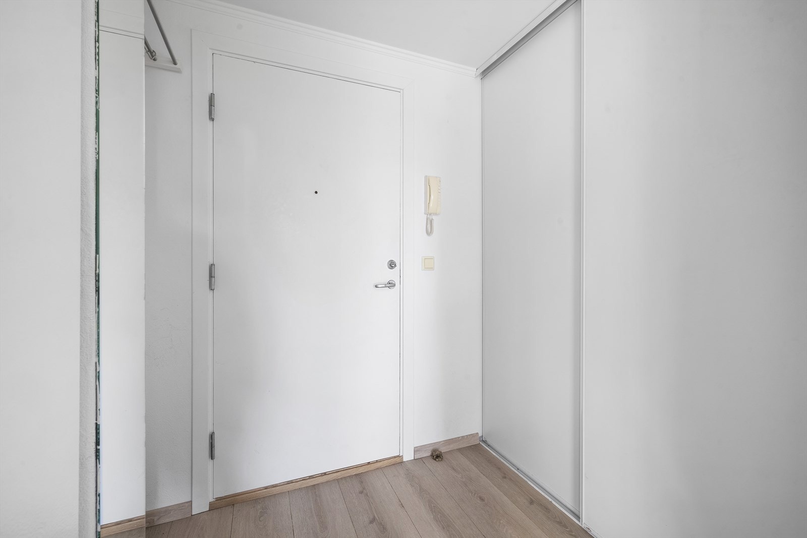 Man kommer inn i en entré med skyvedørsgarderobe, sikringsskap med automatsikringer, og porttelefon som ønsker gjester velkommen. Galleribilde