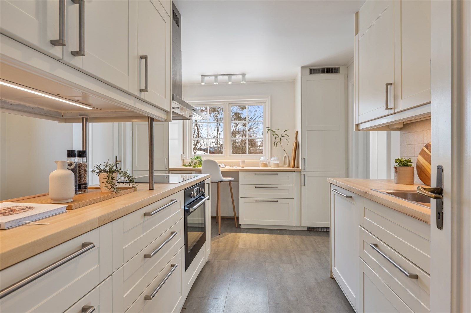 Kjøkkenet er innredet med hvite profilerte fronter og heltre benkeplate. Her er det gode arbeidsflater for den som liger å kokkelere på kjøkkenet. Galleribilde