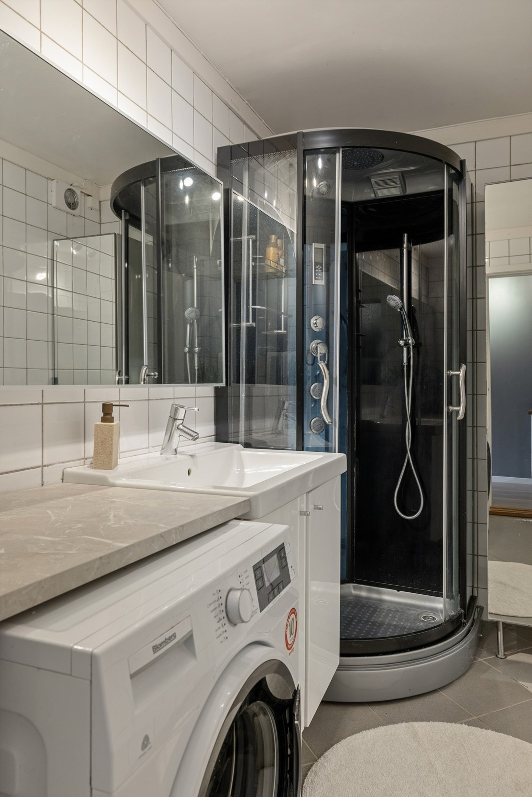 Badet har fliser på veggene og flislagt gulv med elektriske varmekabler, samt malte strier i taket. Galleribilde