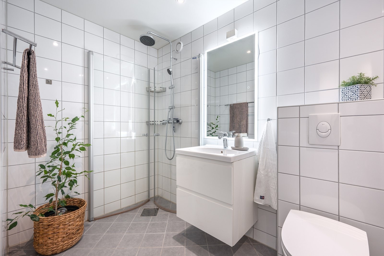 Det er utstyrt med servantskap med heldekkende servant, speil med integrert belysning, veggmontert toalett og dusjhjørne med svingdører og regnfallsdusj. Galleribilde