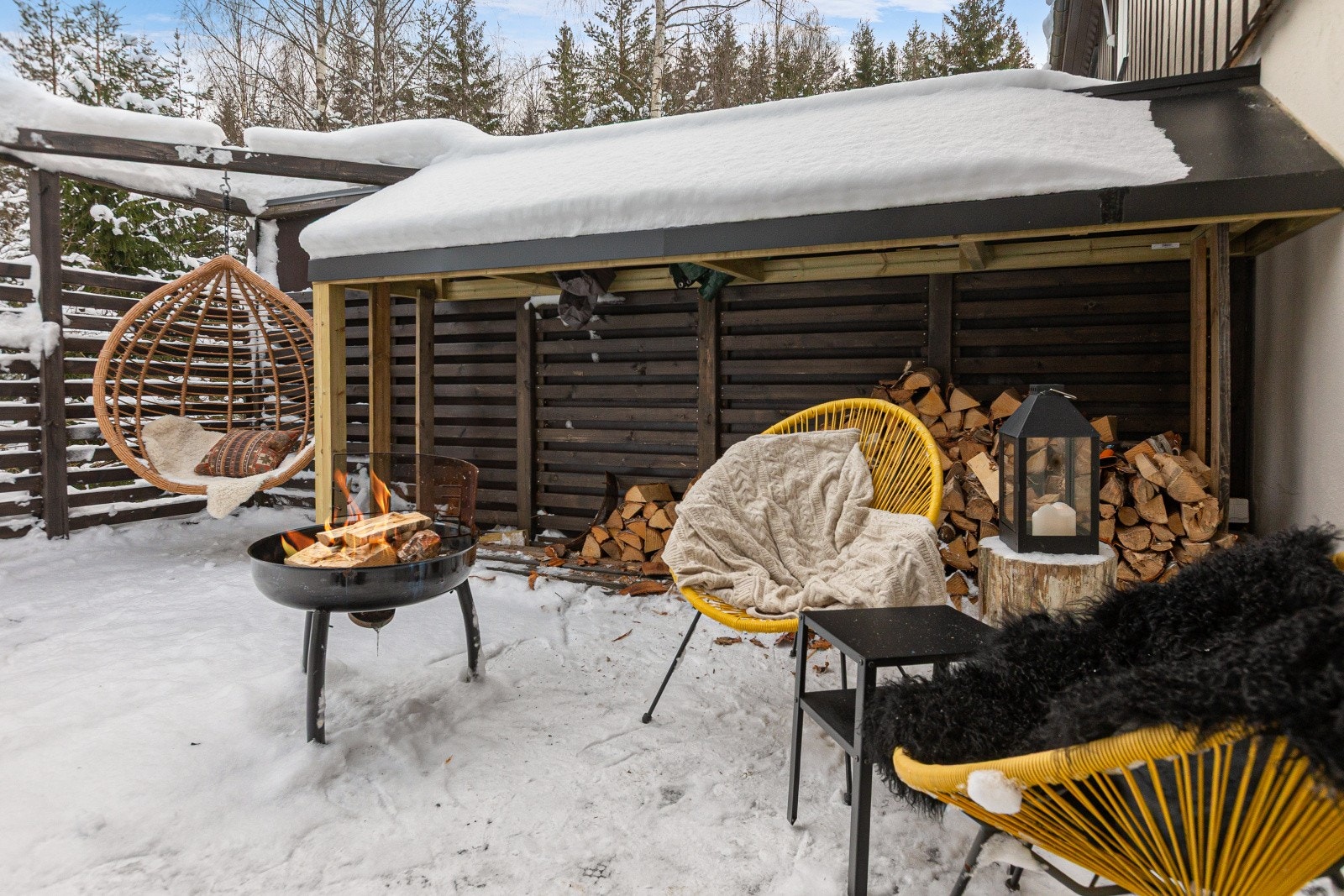 Den overbygde uteplassen gir praktisk ly for ved og utemøbler, og bidrar samtidig til gode oppbevaringsmuligheter utendørs. Galleribilde