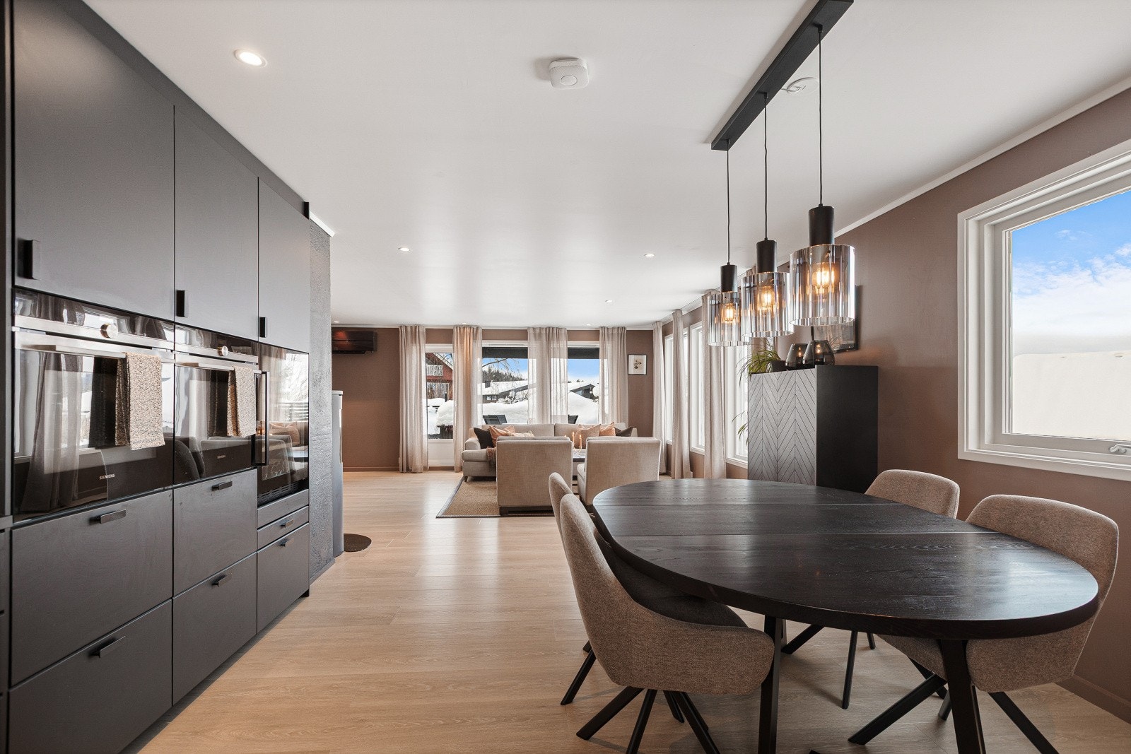 Den åpne løsningen binder kjøkken og stue sømløst sammen til et sosialt og innbydende allrom - perfekt for både hverdagsliv og hyggelige sammenkomster. Galleribilde